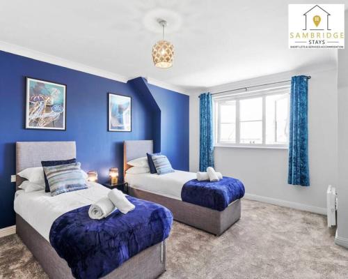 twee bedden in een kamer met blauwe muren bij The Penthouse 3 Bedroom Apartment by Sambridge Stays in Watford
