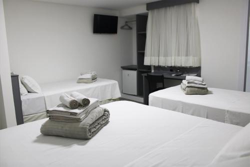a hotel room with two beds with towels on them at Hotel Sagres Praia in Balneário Camboriú