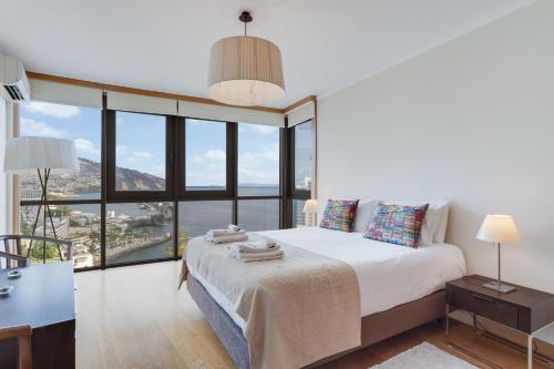 a bedroom with a bed and a large window at Funchal View Apartment in Funchal