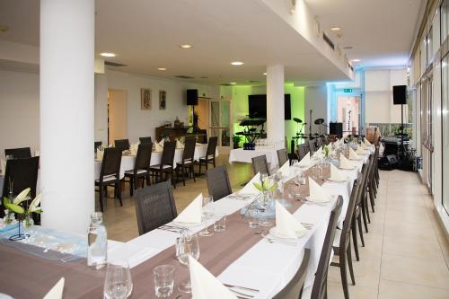 een lange eetkamer met witte tafels en stoelen bij Hotel Kozana in Dobrovo