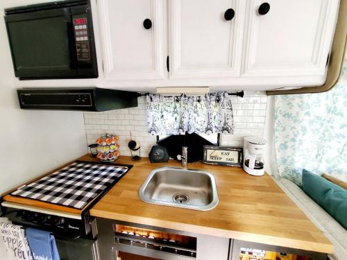 una pequeña cocina con fregadero y microondas en 34ft Mobile Home Near Yale U en New Haven