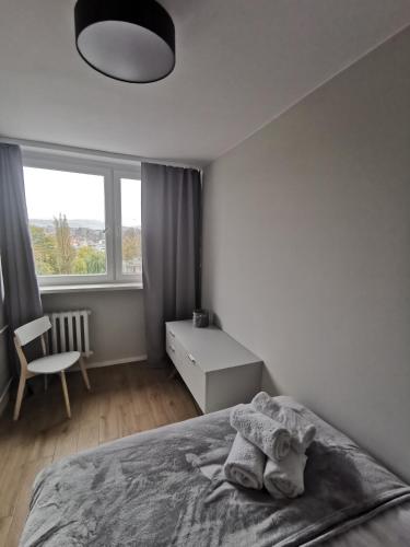 een witte slaapkamer met een bed en een raam bij Apartament Manhattan in Kłodzko