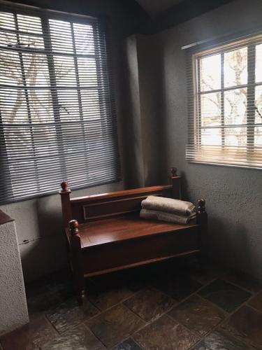 a bench in a corner of a room with two windows at Kruger Ranch in Magaliesburg
