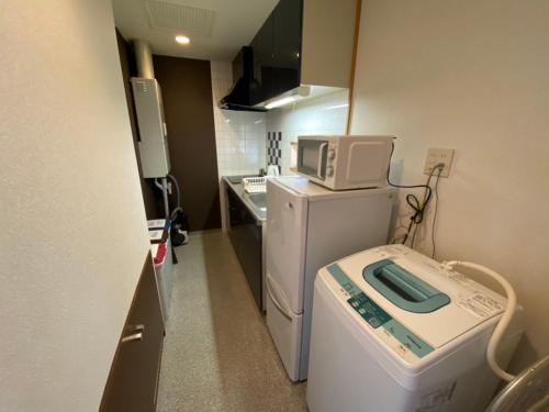 a kitchen with a microwave on top of a washing machine at AMSタワー中島 in Sapporo