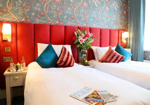 two beds in a hotel room with a book at Kilronan House in Dublin
