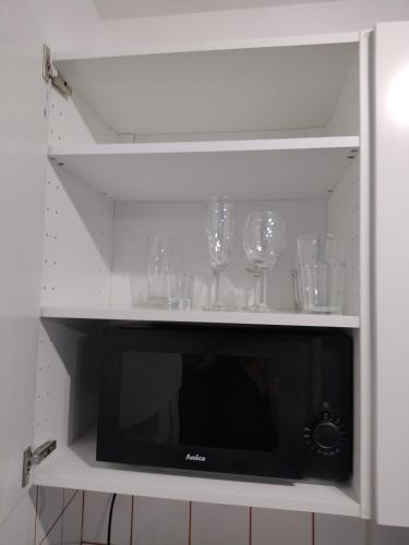 półka z kieliszkami do wina i kuchenką mikrofalową w obiekcie Dolina 21 w Poznaniu