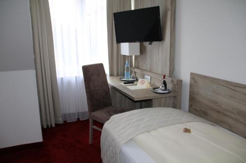 a hotel room with a bed and a desk with a television at Hotel Rosengarten in Bad Salzuflen