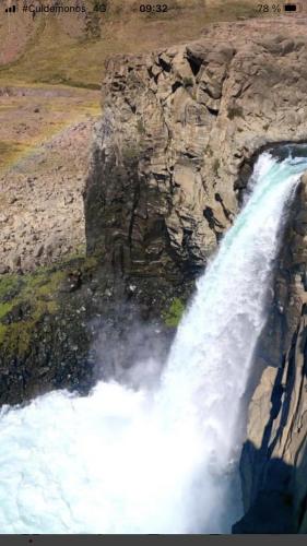 a waterfall on the side of a rocky cliff at Cabaña En Lago colbun, sector Pasó Nevado in Talca