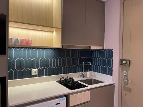 Gold Coast Apartemen PIK by Dluxx في جاكرتا: مطبخ مع حوض و كونتر توب