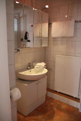 a white bathroom with a sink and a mirror at Hotel Rosengarten in Bad Salzuflen