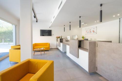 a living room with a yellow couch and a counter at Horizon Hotel Badesi in Badesi