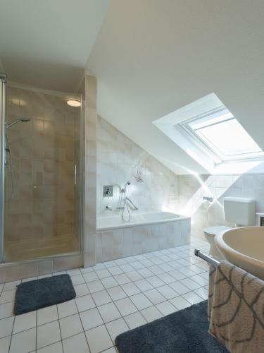 a bathroom with a shower and a tub and a sink at Ferienwohnung Lohrig in Weiskirchen