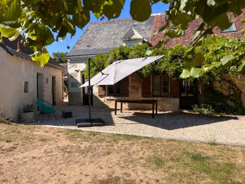 a picnic table with an umbrella in front of a house at La Maison de Frédéric in Francueil