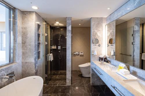 a bathroom with a tub and a toilet and a sink at Holiday Inn Incheon Songdo, an IHG Hotel in Incheon