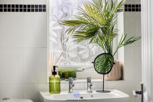 a bathroom with a sink with a mirror and a plant at Coventry Stunning House, 3 double beds, Birmingham Airport NEC, Sleeps 7, by EMPOWER HOMES in Coventry