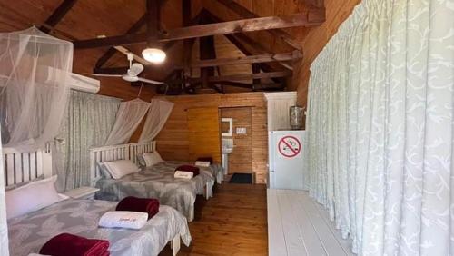 um quarto com 4 camas num quarto com tectos em madeira em Inhaca Kanimambo Lodge 