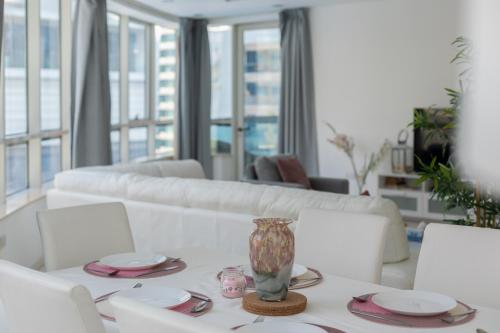 Dubai Marina - 5 bedroom, resort feel, great Amenities في دبي: غرفة معيشة مع طاولة بيضاء مع إناء عليها