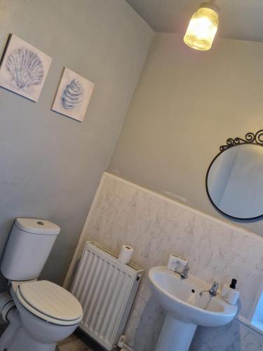 ein Badezimmer mit einem WC, einem Waschbecken und einem Spiegel in der Unterkunft Three Bedroomed House in Morecambe in Morecambe