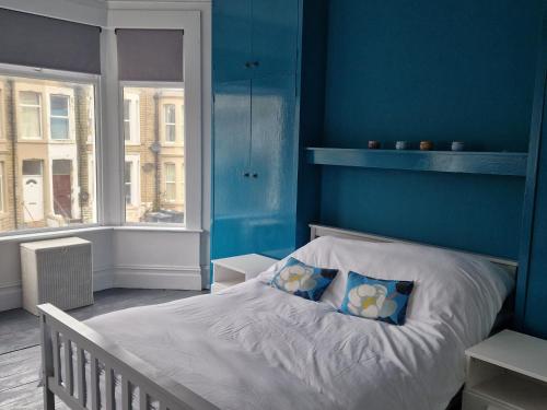 Schlafzimmer mit einem Bett mit blauer Wand in der Unterkunft Three Bedroomed House in Morecambe in Morecambe