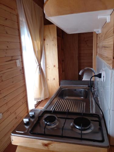a stove top in a small kitchen with a window at Eco Cabañas Wanderlust in Puerto Puyuhuapi