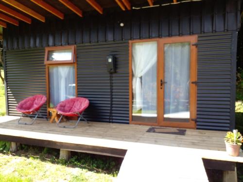 two red chairs sitting on the porch of a tiny house at Eco Cabañas Wanderlust in Puerto Puyuhuapi