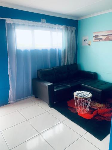 a living room with a black couch and a basketball hoop at Orange Grove in Mthatha
