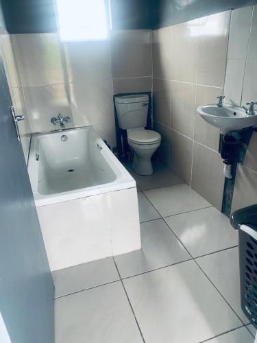 a bathroom with a toilet and a tub and a sink at Orange Grove in Mthatha