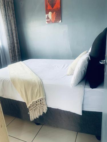 a bed with white sheets and pillows in a room at Orange Grove in Mthatha
