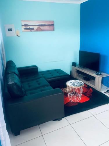 a living room with a black couch and a basketball hoop at Orange Grove in Mthatha