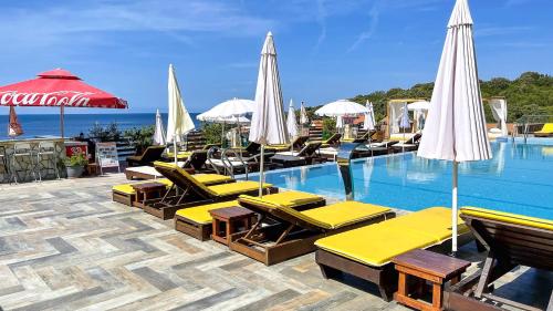 a swimming pool with yellow lounge chairs and umbrellas at Arabela 2 Apartments in Utjeha