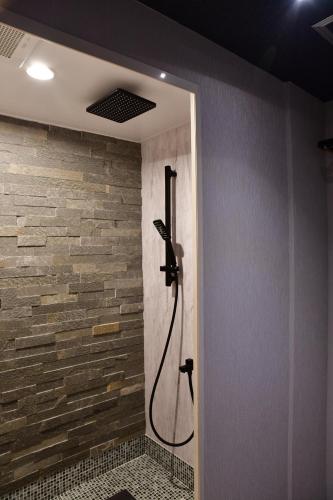 a shower in a bathroom with a stone wall at Villa 33 Kashikojima in Ugata