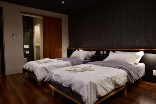 two beds in a hotel room with towels on them at Villa 33 Kashikojima in Ugata