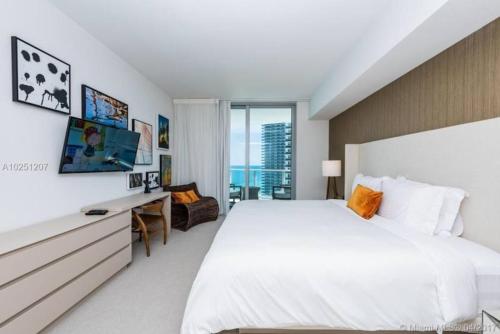 a bedroom with a large white bed and a desk at Modern Beachfront Condo with Stunning Ocean View in Hollywood