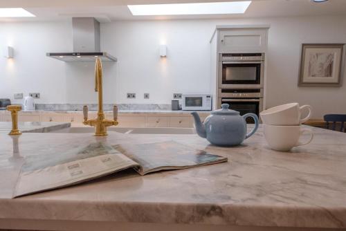 a kitchen counter with a newspaper and a teapot on a table at The Pink House in Southwold in Southwold