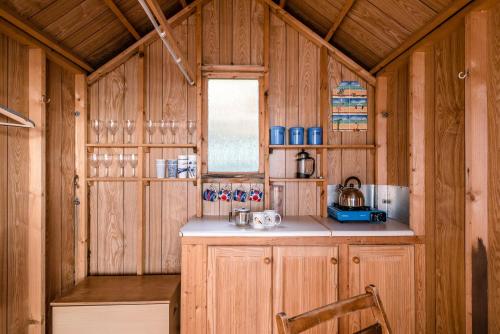 a kitchen with wooden cabinets and a window and a chair at The Pink House in Southwold in Southwold