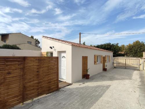 une petite maison blanche avec une clôture en bois dans l'établissement Paisible maisonnette à Entraigues sur la Sorgue, à Entraigues-sur-la-Sorgue