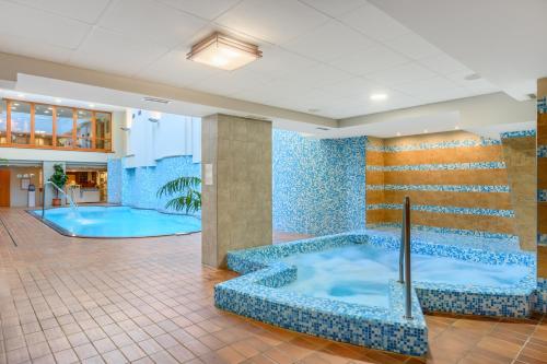 a jacuzzi tub in a lobby with blue tiles at Aranyhomok Business-City-Wellness Hotel in Kecskemét