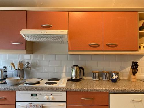 a kitchen with orange cabinets and a stove top oven at Heathpark House in Blairgowrie