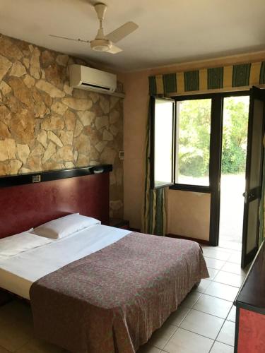 1 dormitorio con cama y pared de piedra en American Motel, en Cisterna di Latina