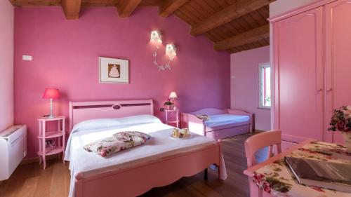 Dormitorio rosa con 2 camas y mesa en CASCINA MARIANNA 12&4, Emma Villas, en Fossombrone