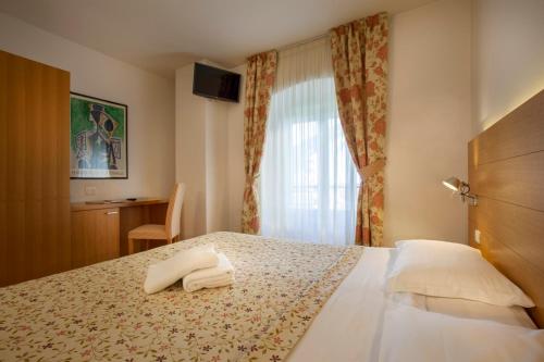 a hotel room with a bed with two towels on it at Hotel Romanda in Levico Terme