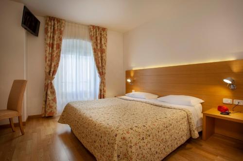 a hotel room with a bed and a window at Hotel Romanda in Levico Terme