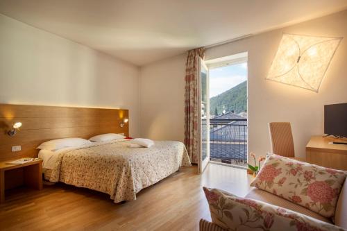 レーヴィコ・テルメにあるHotel Romandaのベッドと大きな窓が備わるホテルルームです。