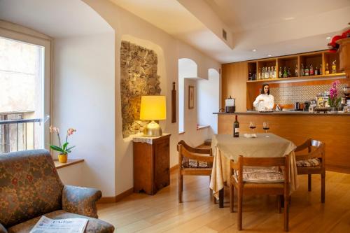 a dining room with a table and a woman in the kitchen at Hotel Romanda in Levico Terme