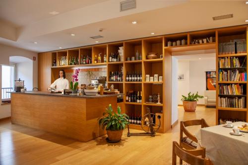 a man standing behind a counter in a room with books at Hotel Romanda in Levico Terme