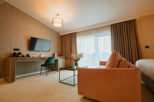 a hotel room with a bed and a couch and a tv at Hotel Stein Collection in Timişoara