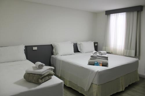 a bedroom with two beds with towels on them at Hotel Sagres Praia in Balneário Camboriú