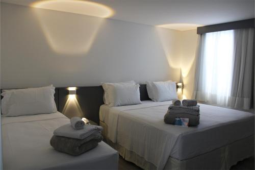 two beds in a hotel room with towels on them at Hotel Sagres Praia in Balneário Camboriú