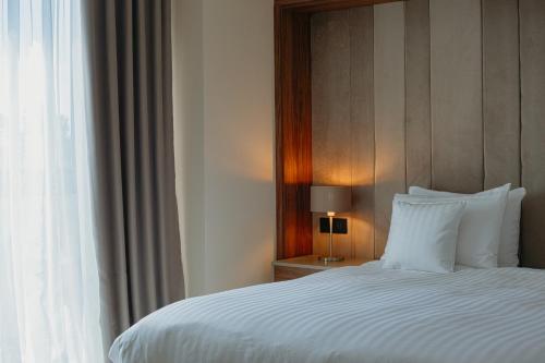 a bedroom with a white bed with a window at Hotel Stein Collection in Timişoara