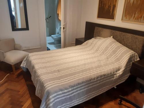 1 cama con manta a rayas en un dormitorio en Av CORDOBA Y FLORIDA 2 AMPLIOS AMBIENTES EXCELENTES en Buenos Aires